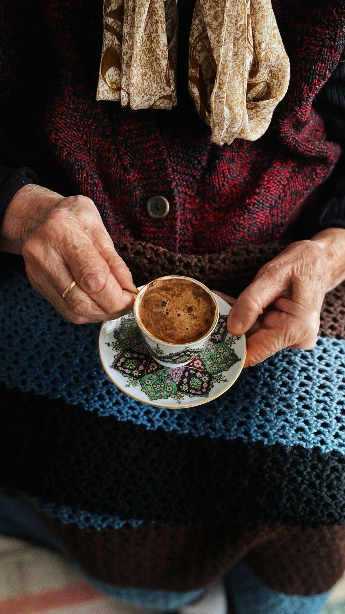 Hände einer älteren Person halten eine Tasse Tee